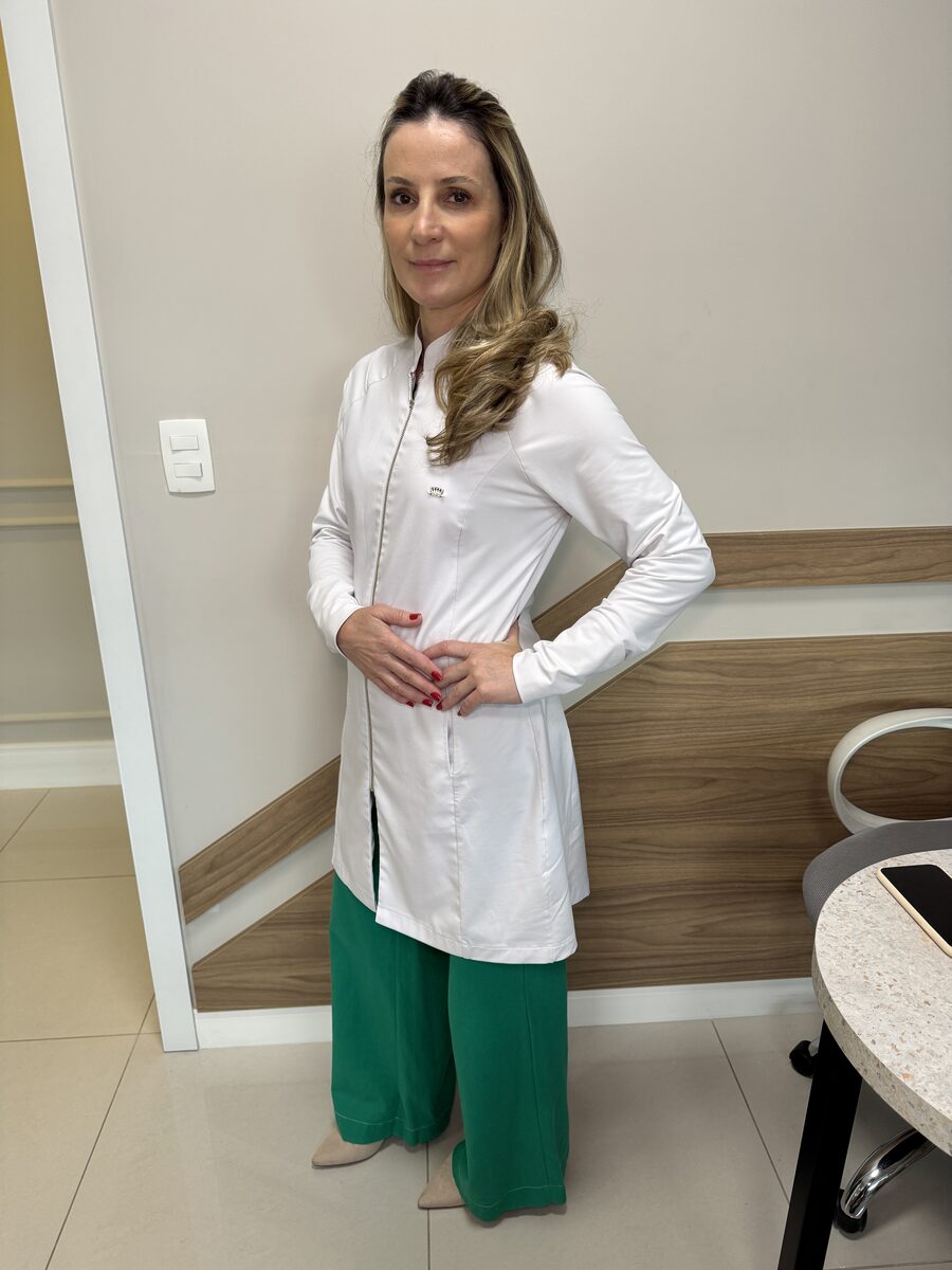 Dra. Gisele Garbelotto de jaleco branco no consultório