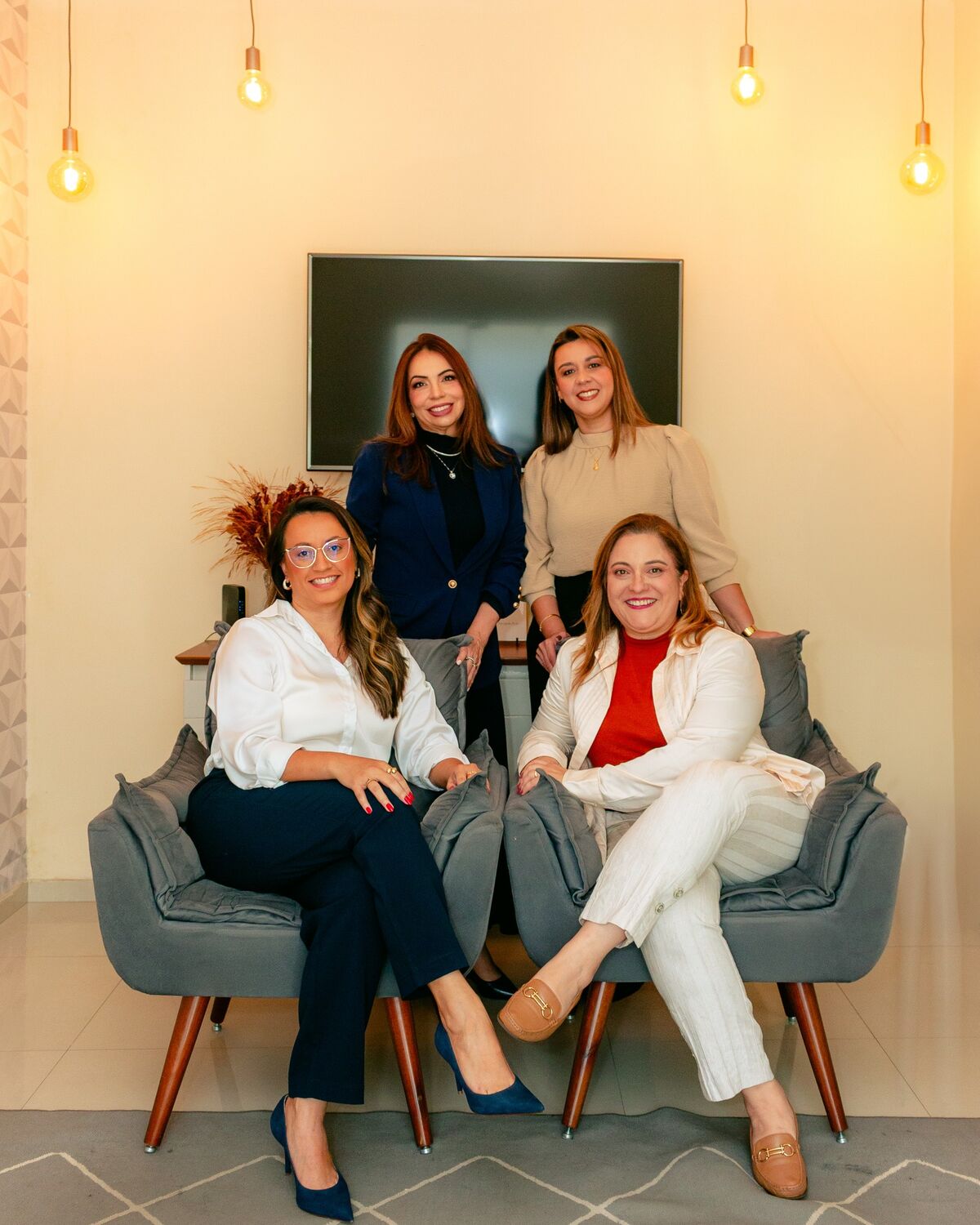 As quatro psicólogas da Mova na recepção do espaço, duas sentadas em poltronas e duas em pé atrás