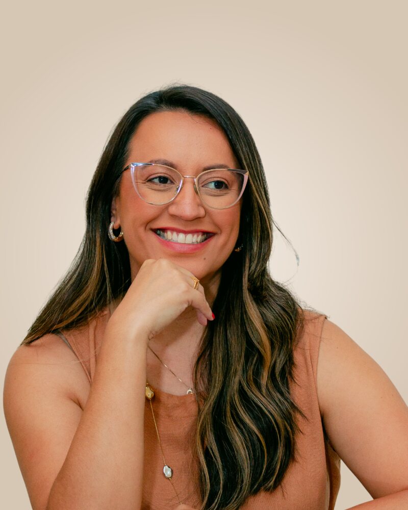 Amanda Moura, psicóloga, sorrindo com a mão no queixo